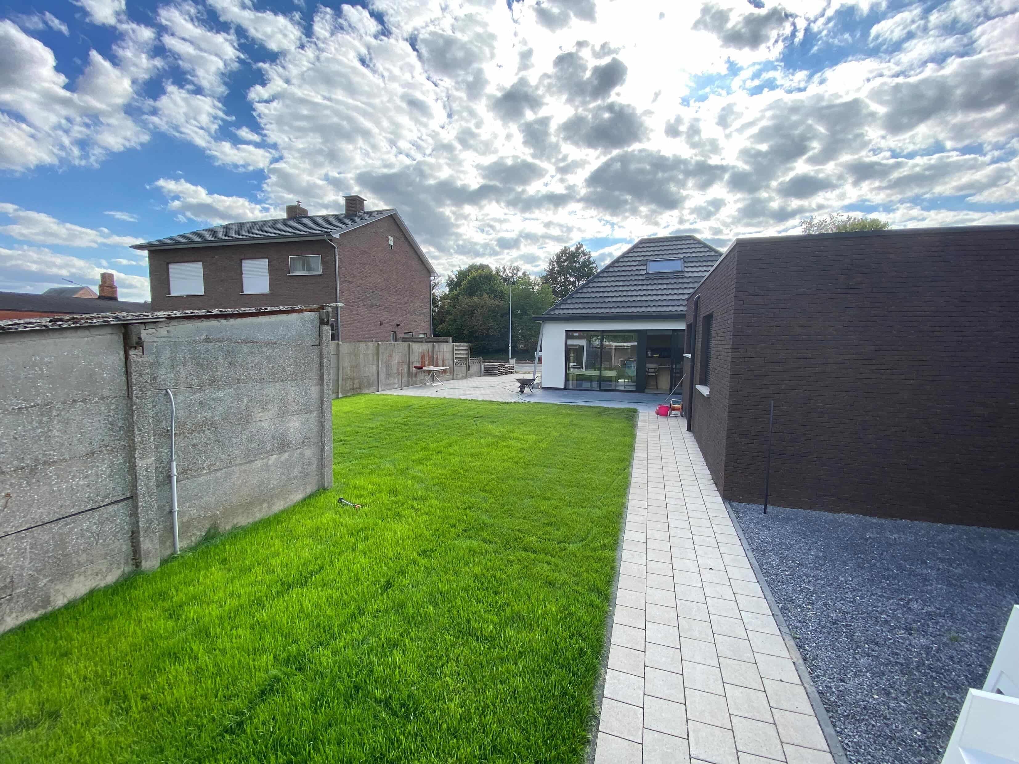 Aangelegde oprit met betonnen tegels en gazon door TuinXpert in Mol