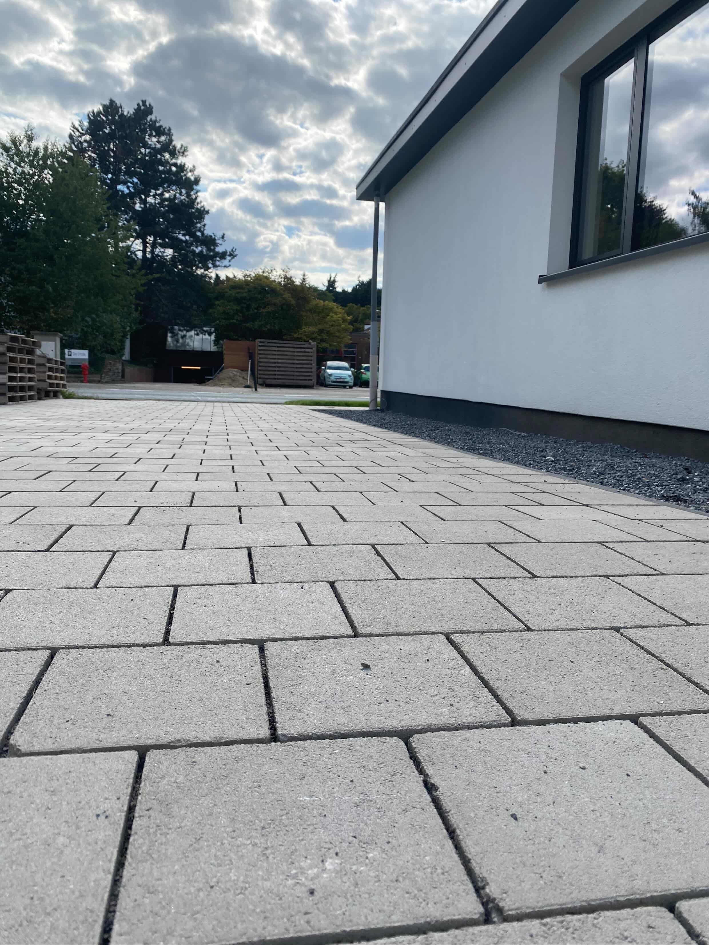 Oprit met betonnen tegels en decoratieve kiezelstroken door TuinXpert